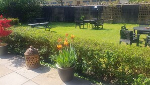 A well-maintained outdoor patio area with a lawn, seating arrangements, and potted plants. - The Shrubbery Hotel (Shepton Mallet)
