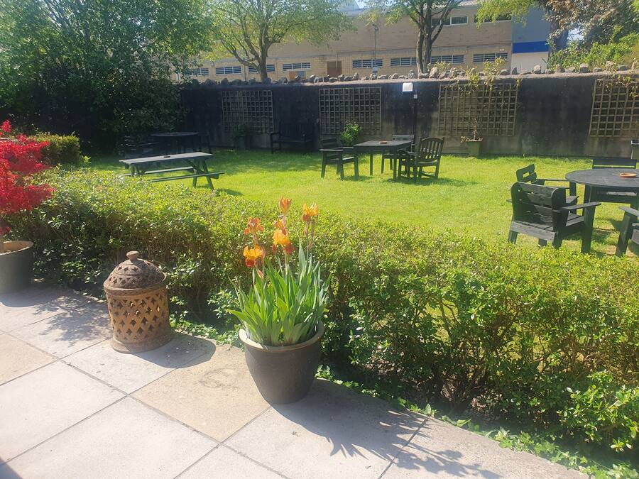 A well-maintained outdoor patio area with a lawn, seating arrangements, and potted plants.