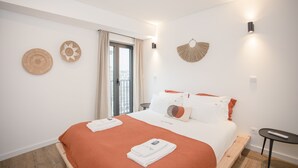 Una camera d'albergo moderna con un letto, un tavolino e vista sulla città dalla finestra.