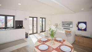 Una cucina moderna con zona pranzo, ampie finestre e angolo salotto.