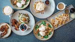 A breakfast spread with various dishes including waffles, bacon, eggs, and a salad. - Stylish Studio in Wola | Air Conditioning and Balcony (Warszawa)