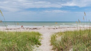 En stig som leder genom sanddynerna och ut till stranden, med gräsbevuxna sanddyner på vardera sidan.