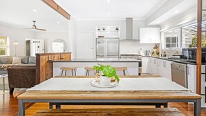 Una cocina moderna con una isla central, electrodomésticos de acero inoxidable y un comedor con mesa y sillas de madera.