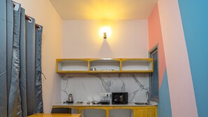 Una cocina compacta con una mesa y sillas de madera, microondas integrado y estantería.