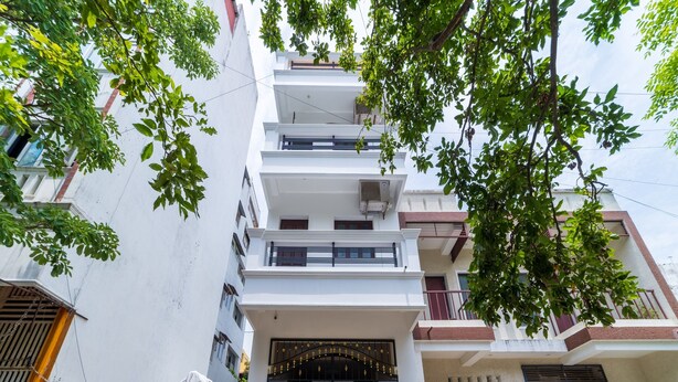 Un edificio residencial de varios pisos con una entrada central que presenta una reja negra con detalles dorados.