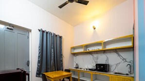 Una cocina compacta con una mesa y sillas de madera, un microondas y un lavamanos.