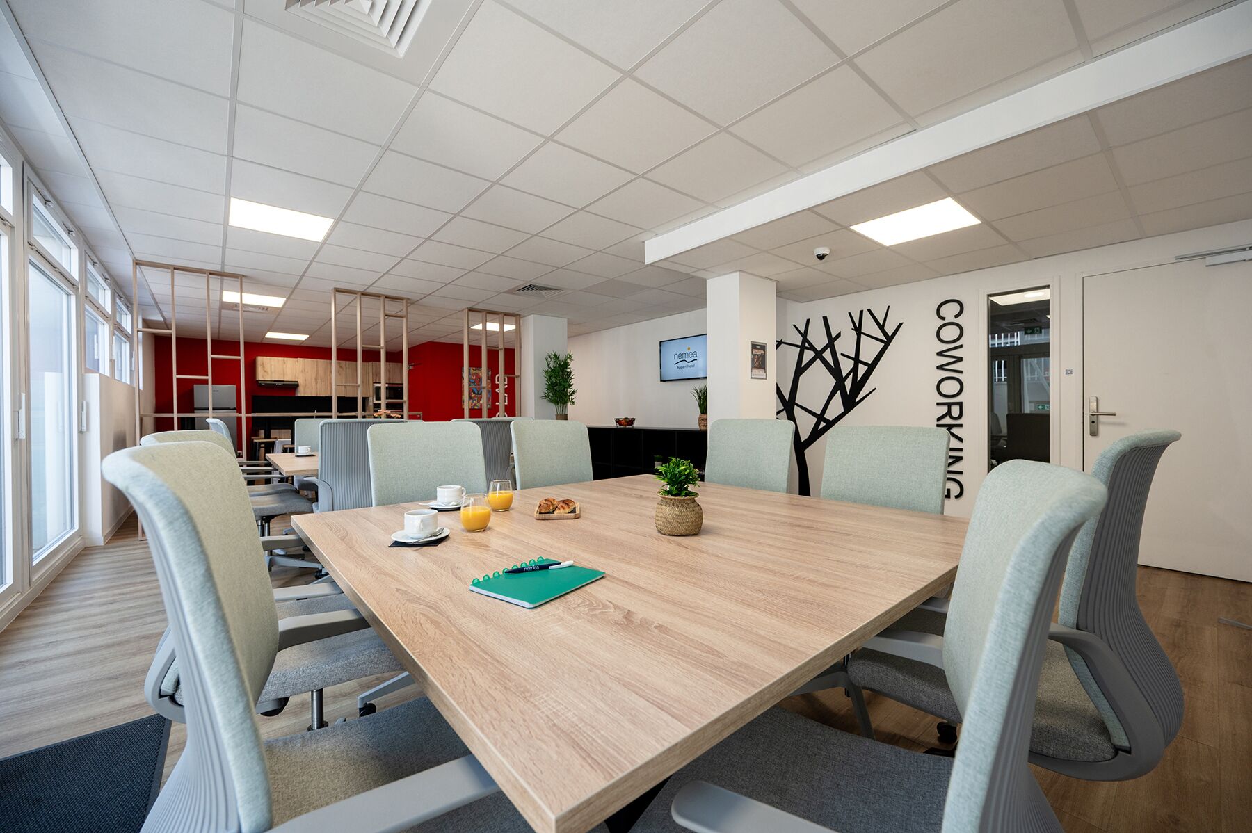 Kokoushuone, jossa on pitkä pöytä, tuoleja ja seinällä kyltti, jossa lukee ”Coworking”.