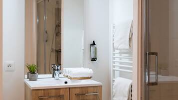 A modern bathroom with a wooden vanity, a large mirror, a shower, and a glass-enclosed shower area.