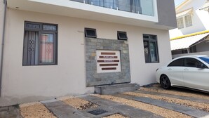 A modern two-story residential building with a stone facade, a gated entrance, and a parked white car. - Brand new Private self catering Apartment situated in Flic en Flac (Flic en Flac)