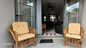 A balcony with wicker chairs and a glass door leading to a living area. - Brand new Private self catering Apartment situated in Flic en Flac (Flic en Flac)