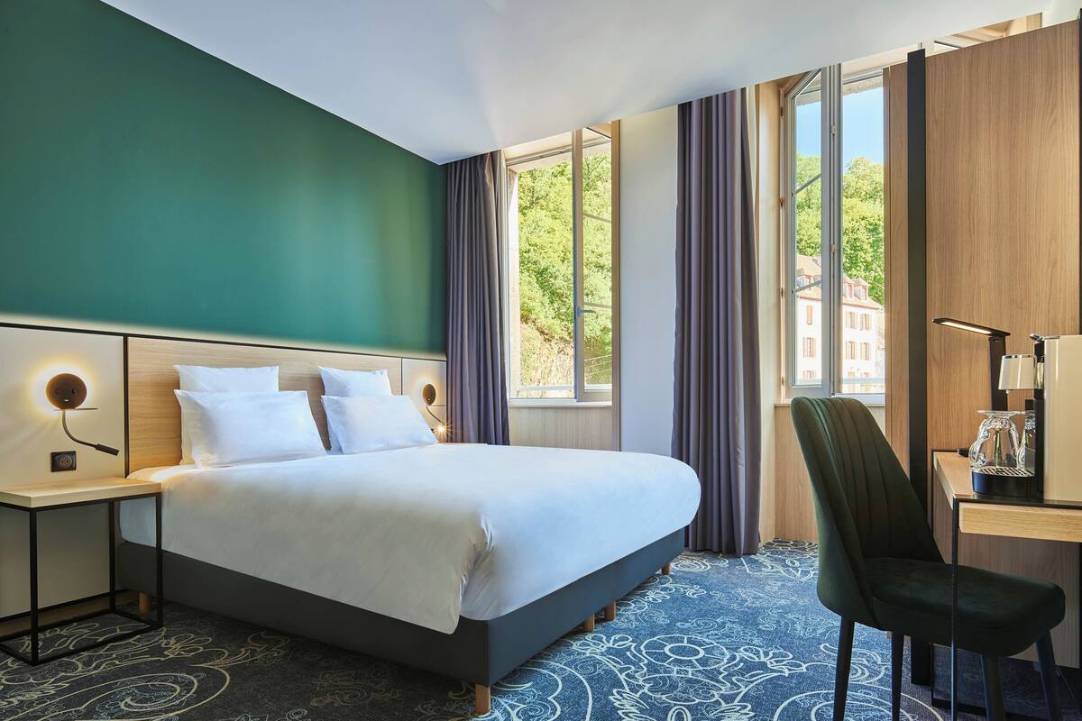Una habitación de hotel con una cama grande, un escritorio y una silla.