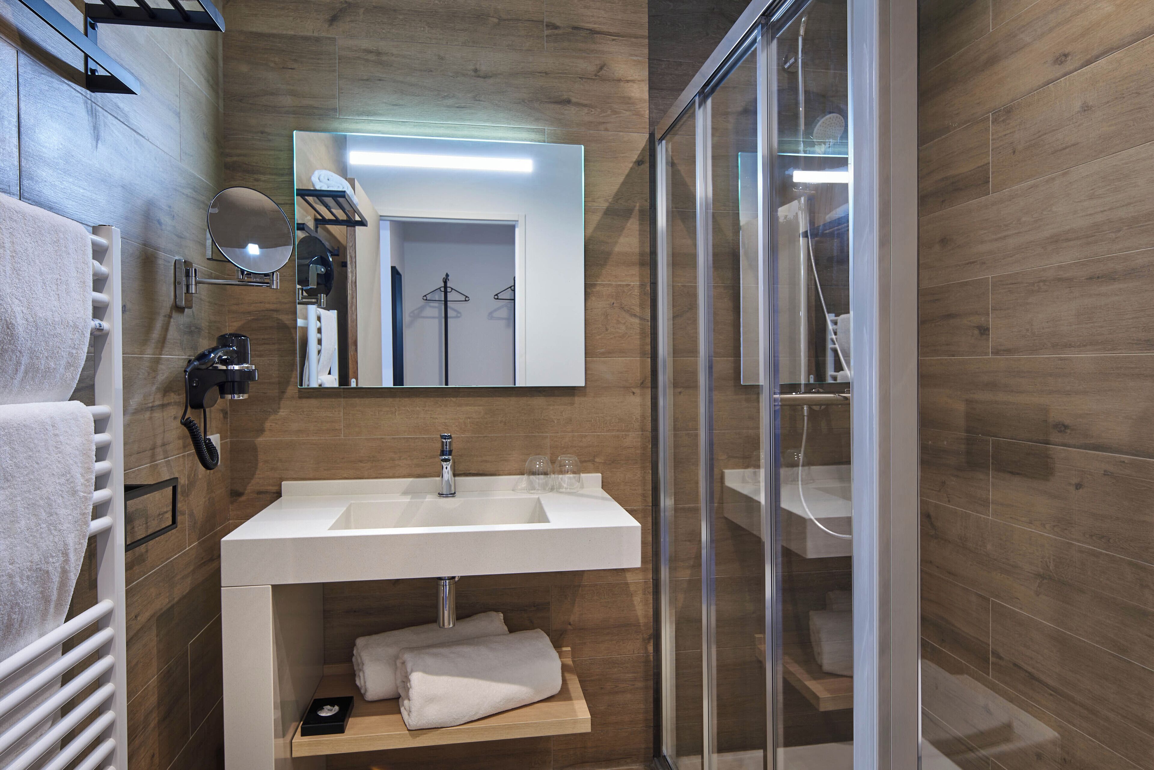 Ein modernes Badezimmer mit Waschbecken, Spiegel und Duschkabine aus Glas.