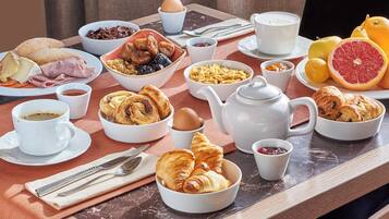 A breakfast table with various food items, including pastries, fruits, and beverages.