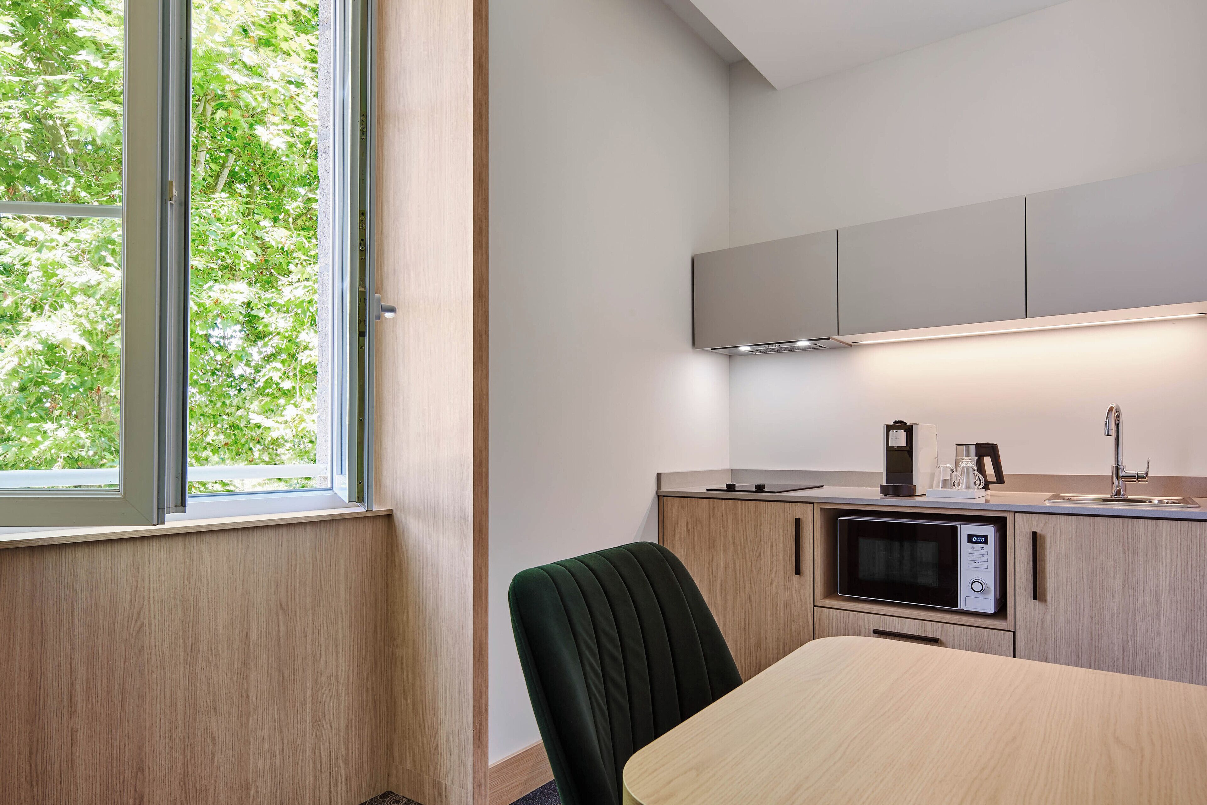 A compact kitchen with a microwave, a coffee maker, and a sink.