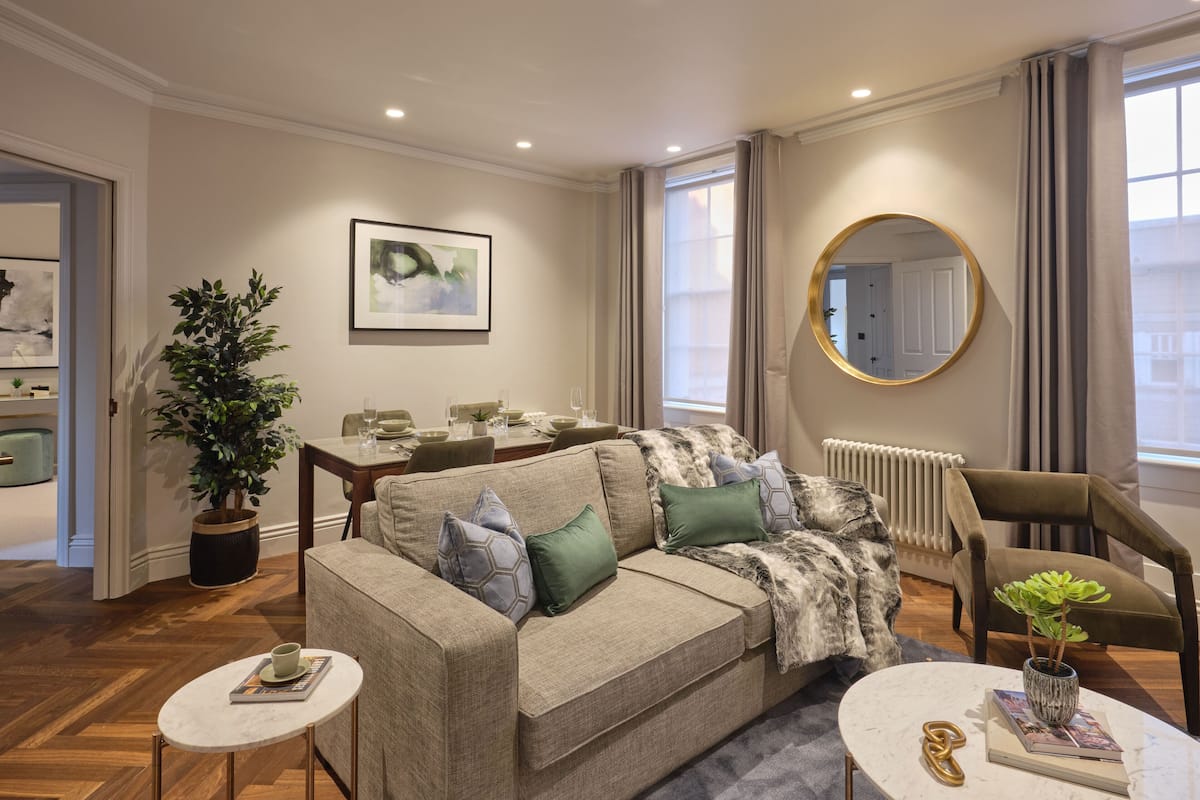A modern living room with a sofa, coffee table, and a dining area.