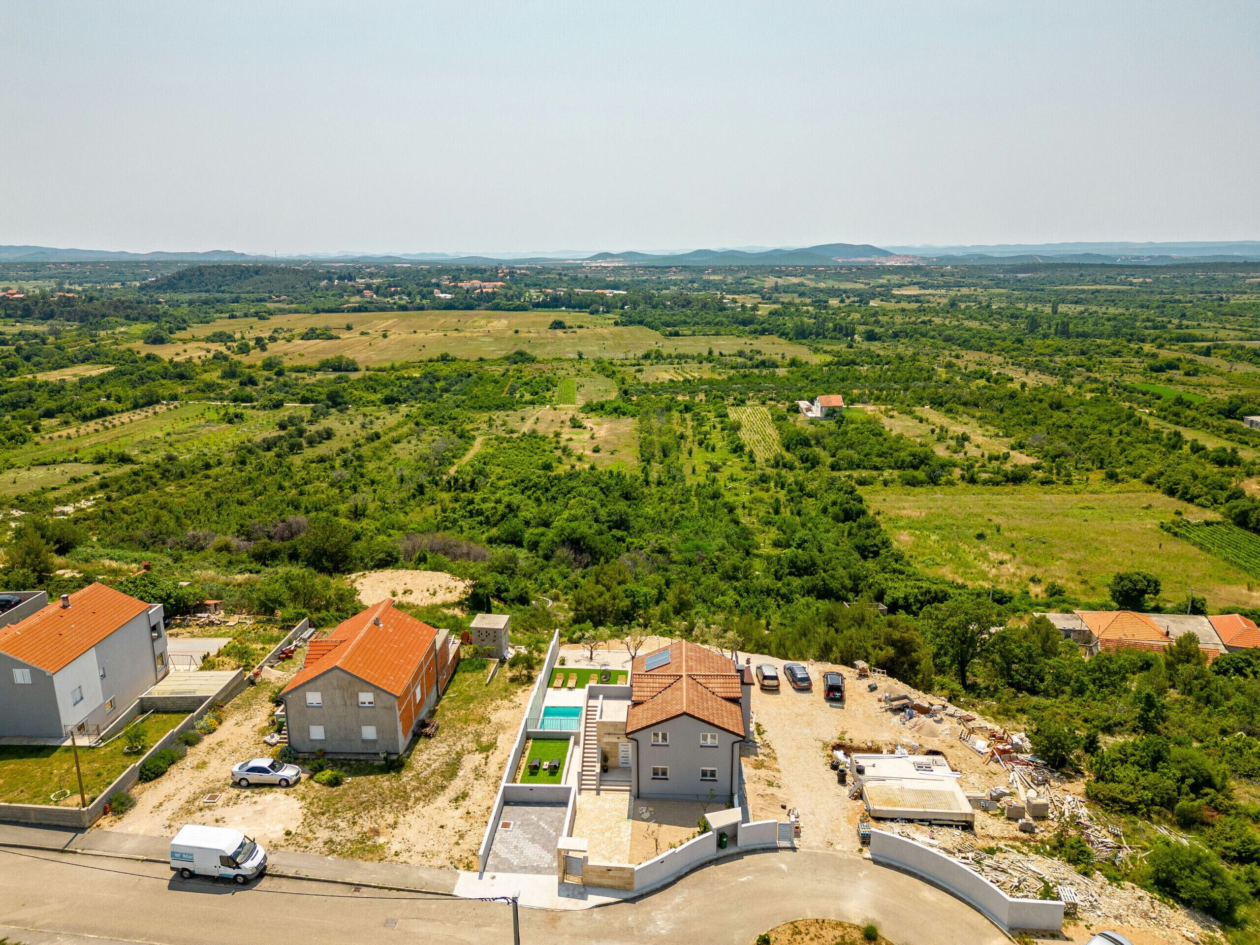 Vue aérienne d’un quartier résidentiel avec des maisons, une route et la végétation environnante.