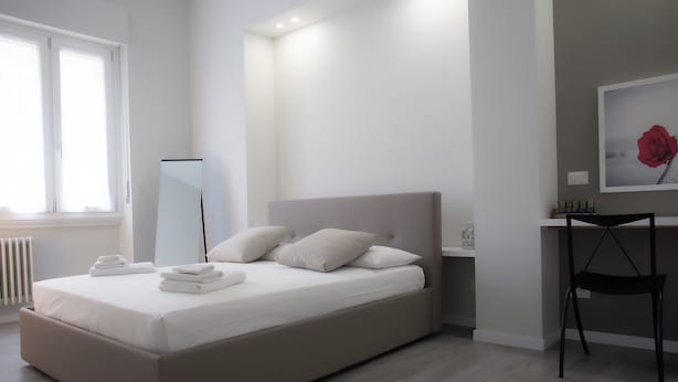 Un dormitorio moderno con una cama grande, una mesita de noche, una silla y una ventana.