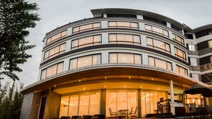 A multi-story hotel with a curved facade, large windows, and outdoor seating area with umbrellas. - THE NORTH STAR HOTEL (Gangtok)