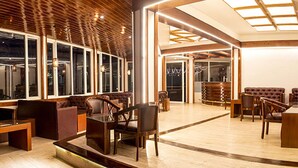 A modern interior with a wooden ceiling, large windows, and a seating area with tables and chairs. - THE NORTH STAR HOTEL (Gangtok)