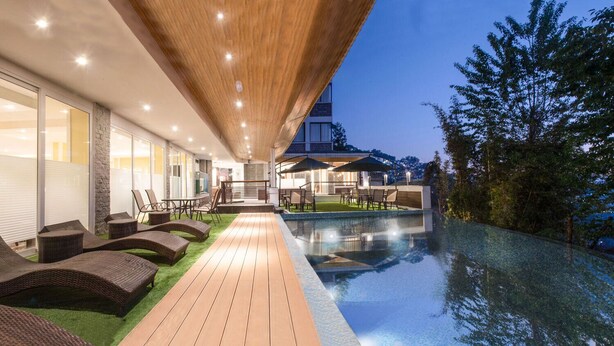 A modern outdoor pool area with lounge chairs and a wooden deck leading to a pool. - THE NORTH STAR HOTEL (Gangtok)