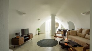 Un salon moderne doté d’un téléviseur à écran plat, d’un canapé, d’une table basse et d’un coin repas avec des chaises et une table.