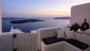 Un espace extérieur aménagé avec des sièges blancs, offrant une vue sur la mer et les îles.