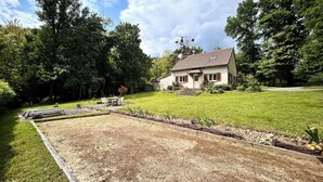 Uma casa com gramado bem cuidado e um espaço de varanda com móveis de exterior.