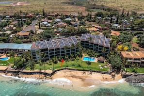 Vista aérea de un complejo turístico con varias edificaciones, una playa y una piscina.