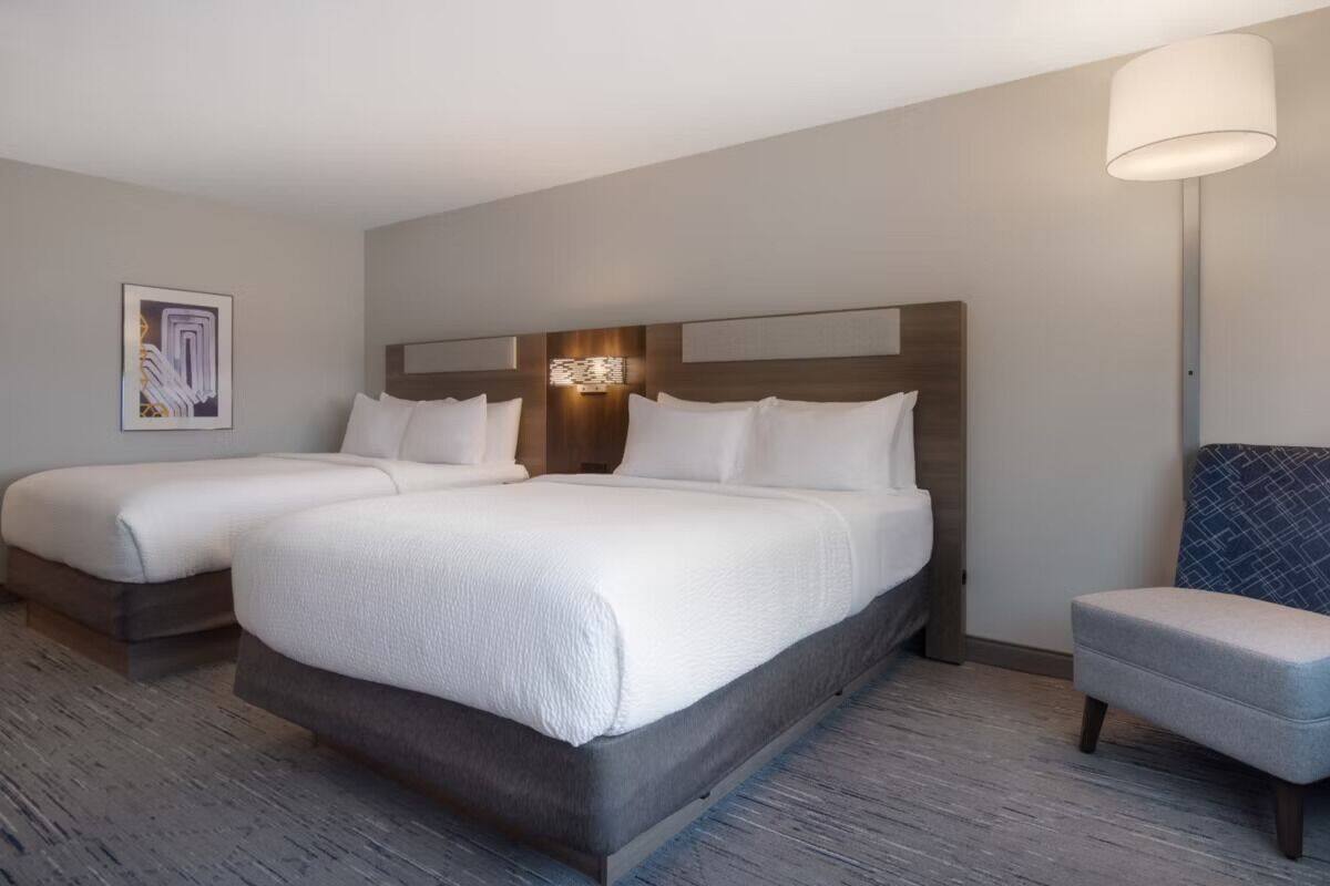 Ett hotellrum med två sängar, en sittgrupp och en väggmonterad lampa.