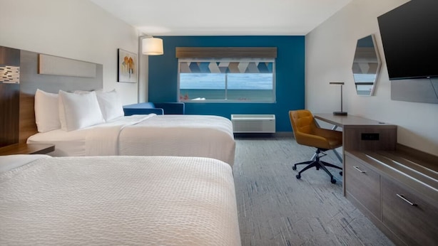 A hotel room with two beds, a desk, a chair, a TV, and a window with a view of the sea. - Holiday Inn Express and Suites Oscoda by IHG (Oscoda)