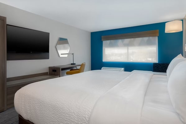 A hotel room with a large bed, a flat-screen TV mounted on the wall, a desk with a chair, and a window with a view. - Holiday Inn Express and Suites Oscoda by IHG (Oscoda)