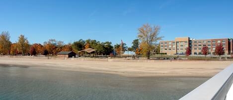 A waterfront hotel with a sandy beach, a covered pavilion, and a multi-story building with a sign for the Holiday Inn Express.