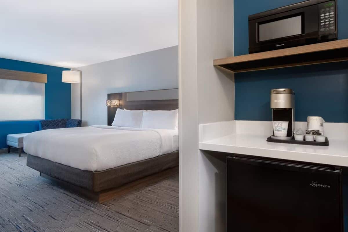 Ett hotellrum med en säng, ett skrivbord med en kaffebryggare och en mikrovågsugn.