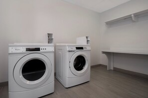 Two front-loading Whirlpool washing machines in a laundry room with a wooden floor and white walls. - Holiday Inn Express and Suites Oscoda by IHG (Oscoda)