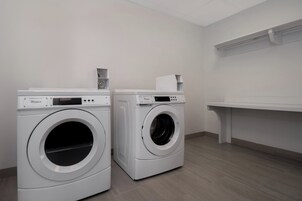 Dos lavadoras Whirlpool de carga frontal en un cuarto de lavado con piso de madera y paredes blancas.
