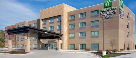 Un hôtel Holiday Inn Express Suites avec une façade en briques, de nombreuses fenêtres et une entrée abritée.