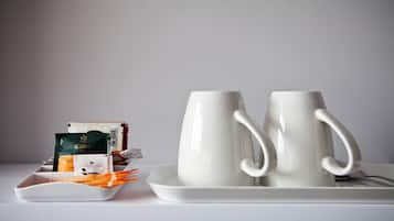 A tray with two white mugs and a plate with food items and a coffee packet.