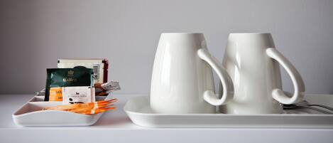 A tray with two white mugs and a plate with food items and a coffee packet.
