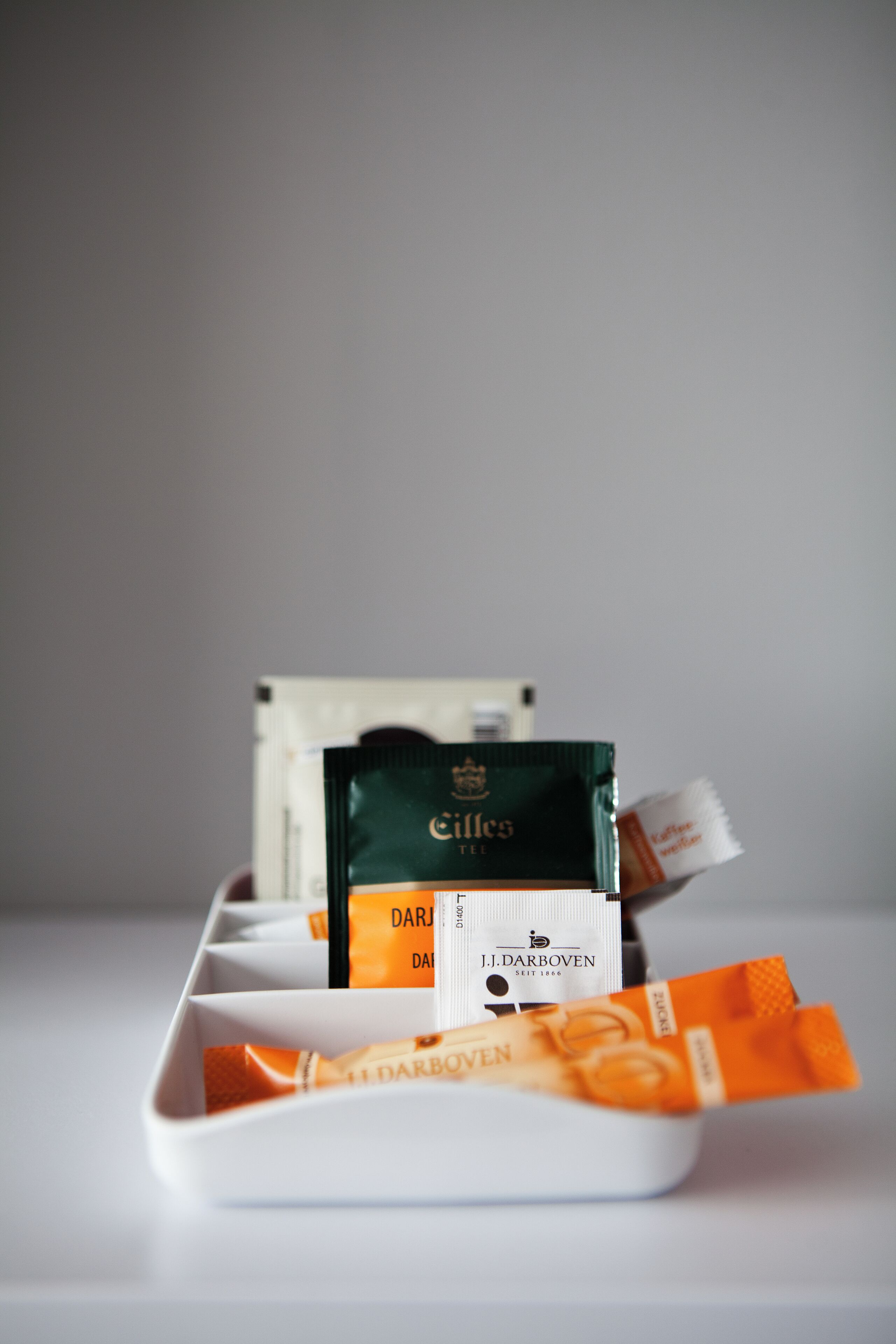 A white tray with several packets of J.J. Darboven tea and a green packet of Cifles tea.