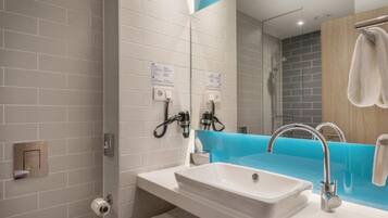 Une salle de bain moderne avec un lavabo blanc, un mur d’accent bleu et un espace douche.