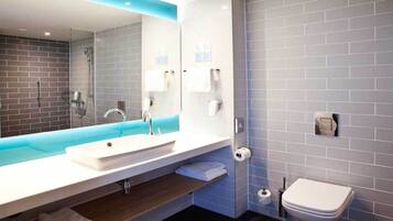 A modern bathroom with a large mirror, a sink, a shower, and a toilet.