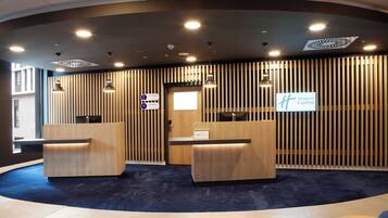 A reception area with two wooden reception desks, a blue carpeted floor, and a sign for Holiday Inn Express.