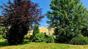 A residential area with a large tree with red leaves, a green tree, and a yellow building in the background. - 8 Coach House (Preston)