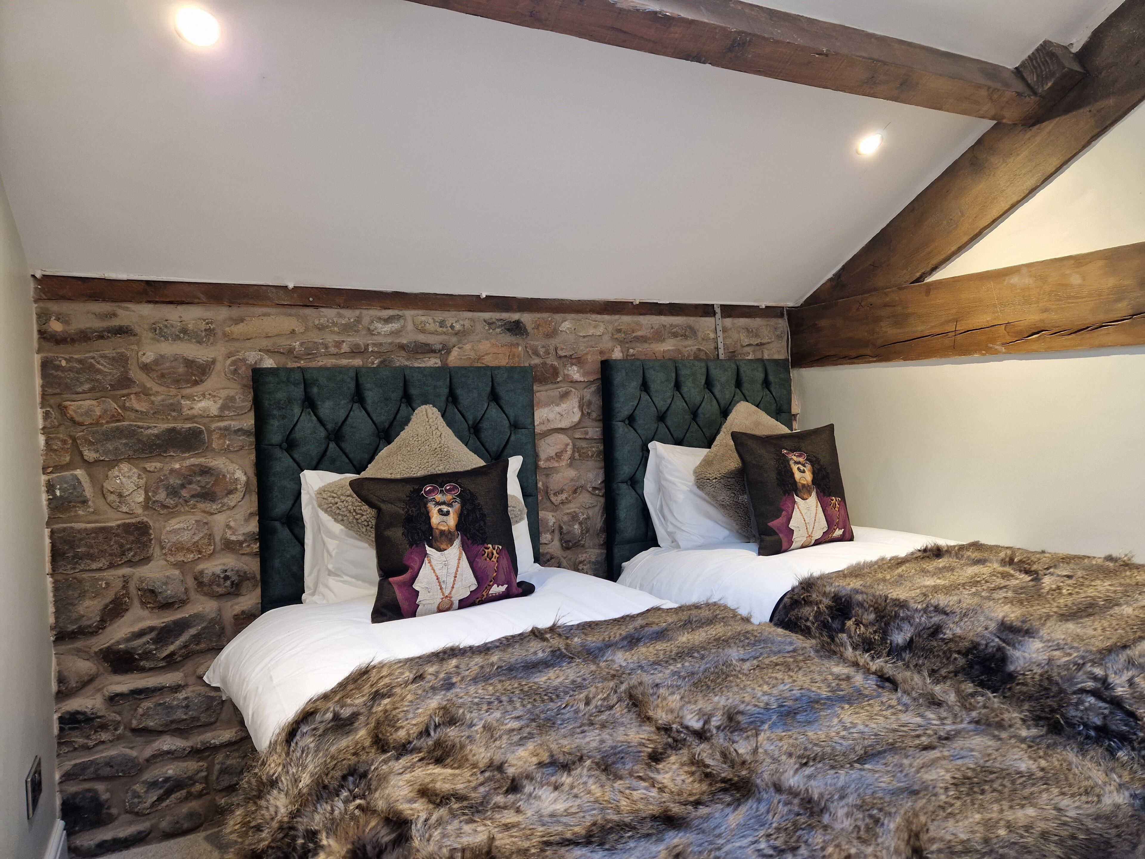 Ein Schlafzimmer mit zwei Betten, Steinwänden und Holzbalken.