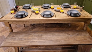 A wooden dining table set with plates, bowls, cutlery, and glasses of orange juice. - 8 Coach House (Preston)