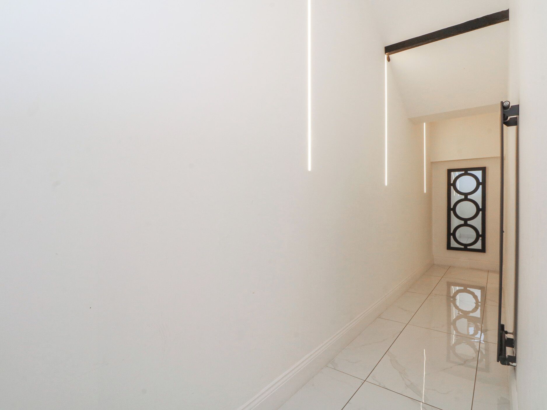 A hallway with a tiled floor and a decorative metal gate.
