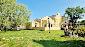 A yellow house with a large lawn, a wooden fence, and a street lamp. - 7 Holly Barn (Preston)