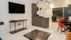 A modern kitchen with a central island, a dining area with orange chairs, and a flat-screen TV mounted on the wall. - 7 Holly Barn (Preston)
