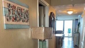A kitchen with a wooden countertop, a decorative wall piece, and a view into the dining area. - Stunning direct ocean front 2 bedroom unit! Fully equipped and all remodeled! (New Smyrna Beach)