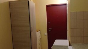 Una habitación pequeña con un armario de madera, una puerta roja y una lavadora.